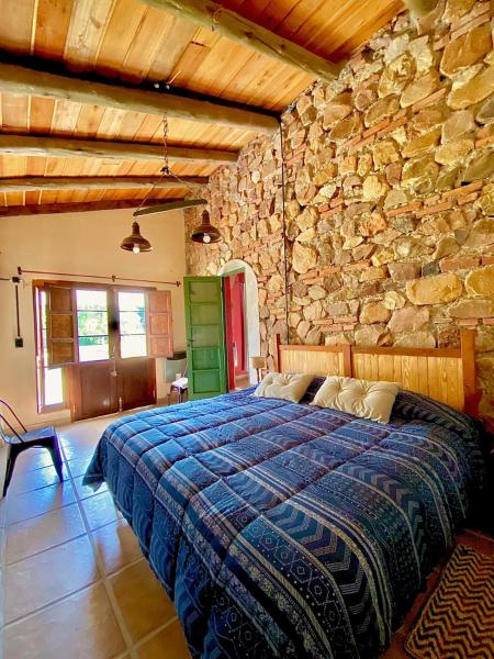 1 dormitorio con 1 cama en una pared de piedra en Finca La Secundina en Salta