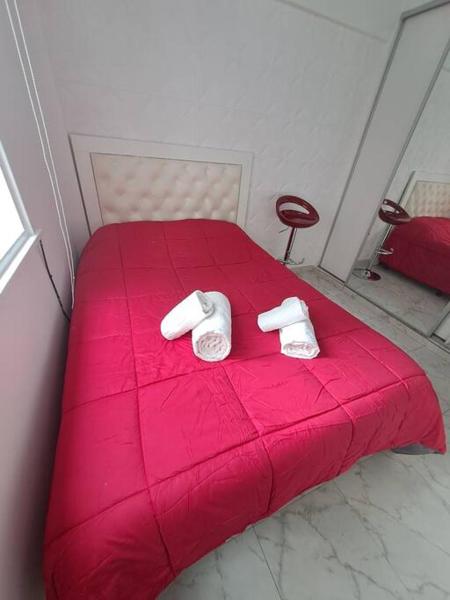 Una cama roja con dos toallas blancas encima. en Departamento de Lujo en la Ciudad Buenos Aires en Buenos Aires