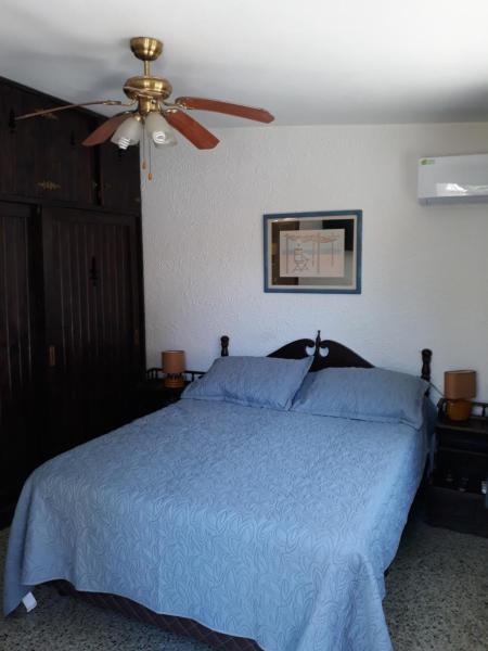 1 dormitorio con 1 cama azul y ventilador de techo en Suíte, en Punta del Este