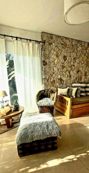 Habitación con pared de piedra, cama y ventana en Arena de Mar depto A en Balneario Mar Azul