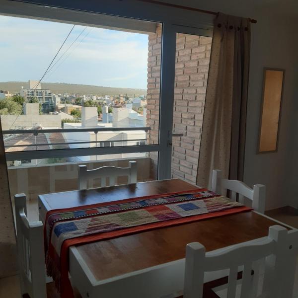 mesa y sillas en una habitación con ventana grande en La Estadía en Puerto Madryn