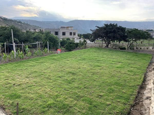 un gran campo de hierba con una casa en el fondo en Casa de Campo Nuestra Tierra, en Quito