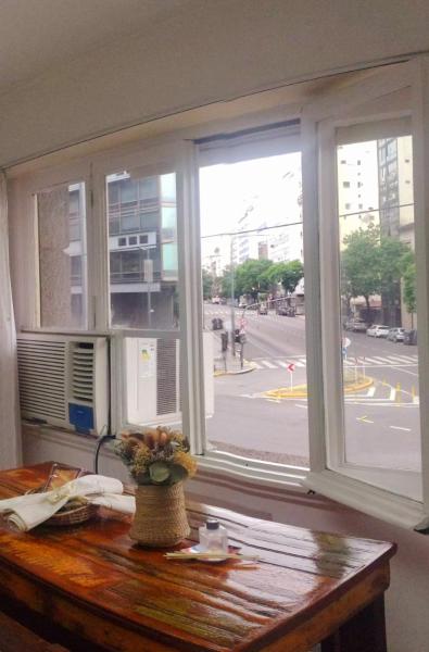una ventana con un jarrón de flores sobre un escritorio de madera en APARTAMENTO OCHAVA Promos x paquetes Conversión Dolar Oficial en Buenos Aires
