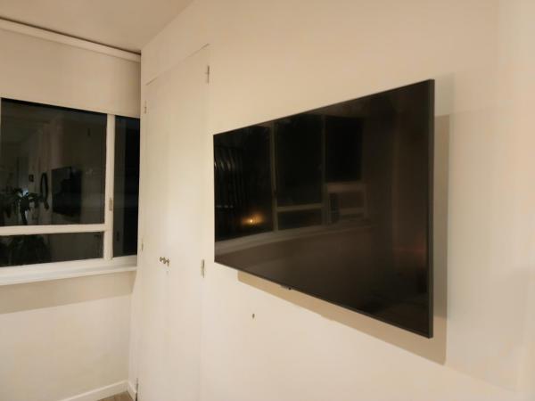 TV grande en la pared en una habitación con 2 ventanas en G&G Apartments - Recoleta Cozy Studio en Buenos Aires