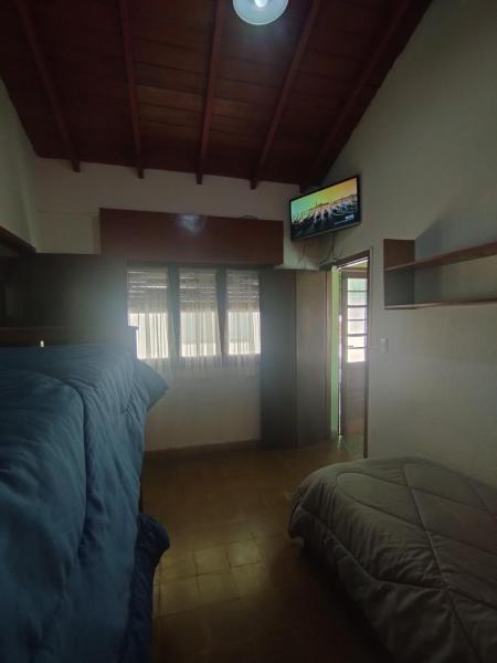 1 dormitorio con 1 cama y TV en la pared en Departamentos Pablos A Villa Gesell en Villa Gesell