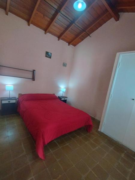 1 dormitorio con 1 cama roja en una habitación en Departamentos Pablos En Villa Gesell en Villa Gesell
