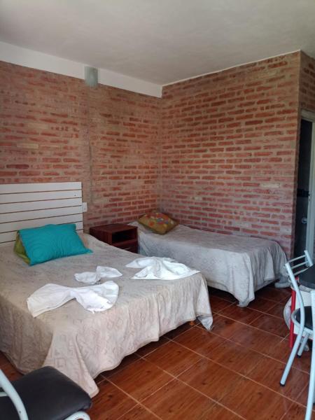 Habitación con 2 camas y pared de ladrillo en Complejo Navi, en Mina Clavero