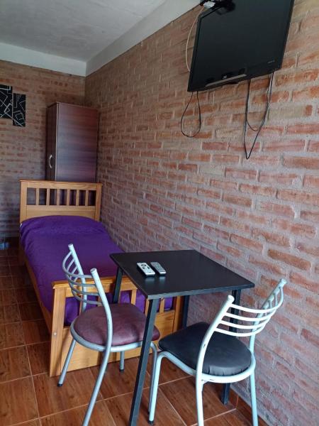 Habitación con cama, mesa y sillas. en Complejo Navi, en Mina Clavero
