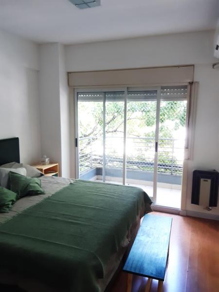 1 dormitorio con cama verde y ventana grande en DEPARTAMENTO DE LUJO EN ALMAGRO en Buenos Aires