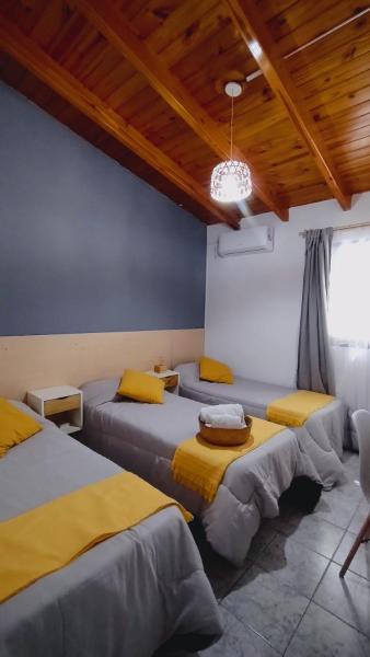 Habitación con 4 camas con sábanas amarillas y techo de madera. en Hotel Alta Mendoza en Mendoza