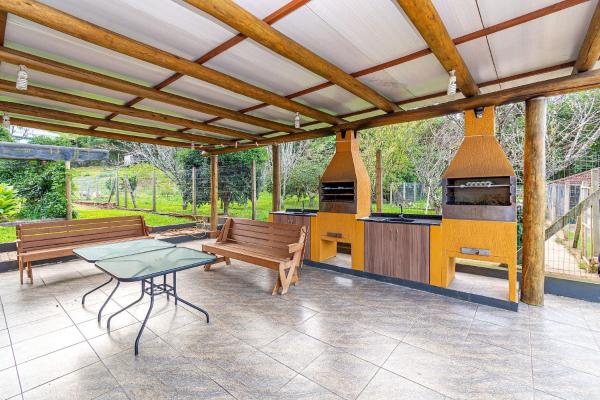 una cocina al aire libre con 2 bancos y una mesa en Rosa Casa Várzea Grande, en Gramado