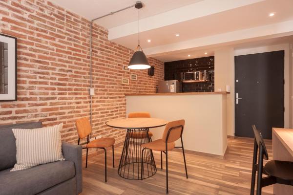 sala de estar con mesa, sillas y pared de ladrillo en Cozy & Modern Luxe Apartment -La Galerie San Telmo- 228 en Buenos Aires