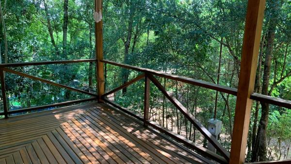 una terraza de madera con vistas al bosque en Casa Monte en Puerto Iguazú
