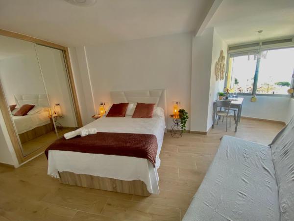 1 dormitorio con 2 camas, mesa y espejo en Lujoso piso con vista al mar en la cala de mijas, en Málaga
