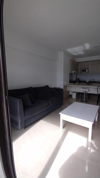 sala de estar con sofá negro y mesa blanca en Azucena Apart II en Salta