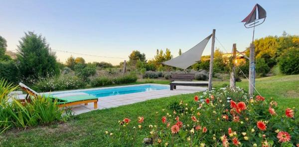 una piscina en un jardín con un banco y flores en Las Roses en Balneario Mar Azul