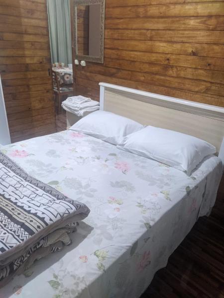 Un dormitorio con una cama blanca con flores. en villa foresti macedo gramado, en Gramado