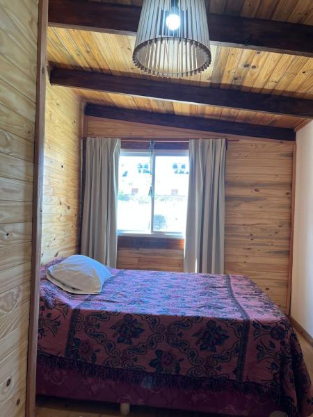 1 dormitorio con 1 cama en una habitación con ventana en Tus cabañas en Las Grutas