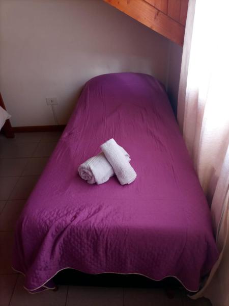Una cama morada con dos toallas encima. en Hospedaje de Ensueño SMA en San Martín de los Andes