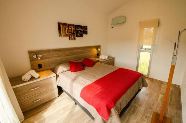 1 dormitorio con 1 cama grande con manta roja en Los Cóndores Aparts. en Villa General Belgrano