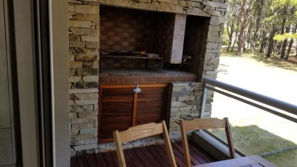 una chimenea de piedra con 2 sillas en el porche en Natureza en Pinamar