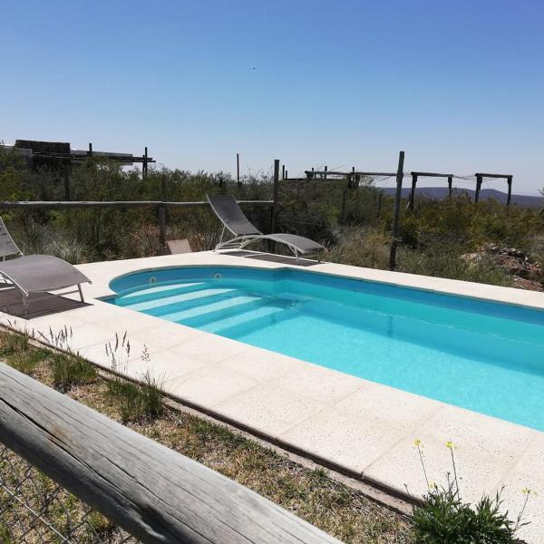 una piscina con 2 sillas de césped en Aguara House, Pedemonte - Mendoza en Mendoza