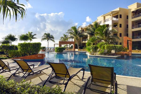 una piscina en un complejo con sillas y palmeras en Spacious beachfront condo True Oceanfront 1bdrm 2bath Surf 308, en Playa del Carmen