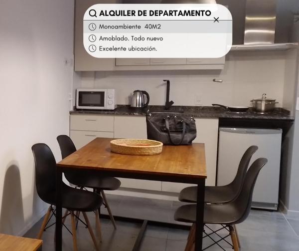 cocina con mesa con sillas y microondas en Bermellon en Mendoza