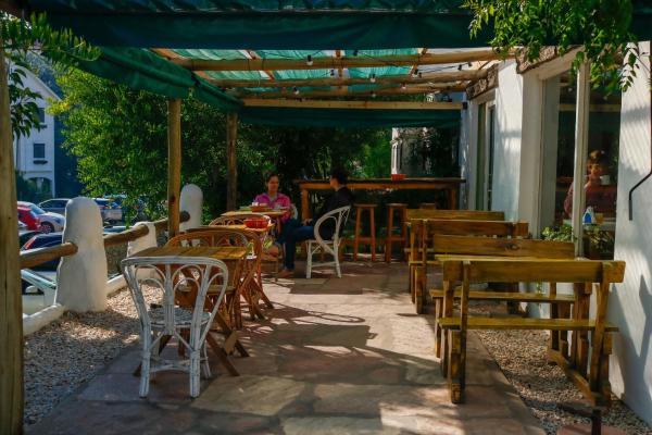 un patio con mesas y sillas bajo una pérgola en África Posada en Pinamar
