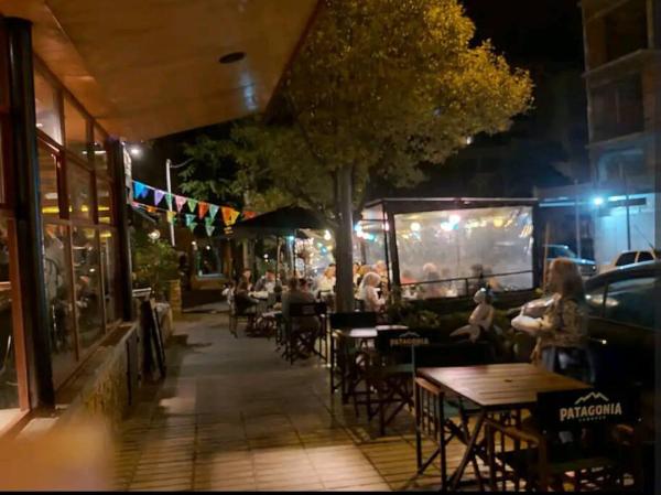 un grupo de personas sentadas en las mesas fuera de un restaurante por la noche en depto alem dahl en Mar del Plata
