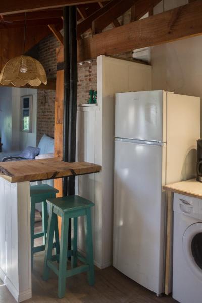 cocina con refrigerador y mesa con taburetes en Pinamar Bosque en Pinamar