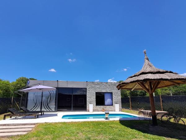 una piscina con sombrilla y una casa en La Mora en Salta