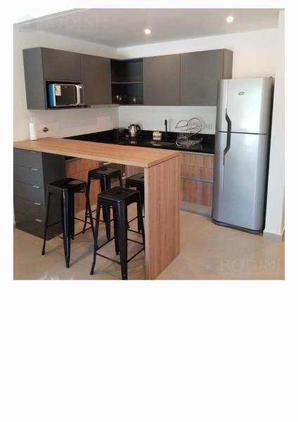 cocina con refrigerador y mesa con taburetes en Pinamar, Complejo Premium en Pinamar Norte en Ostende
