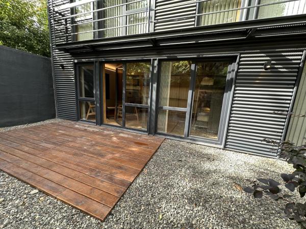 una terraza de madera frente a un edificio en Hermoso departamento de 3 ambientes con amplio jardin. 1V5 en San Martín de los Andes