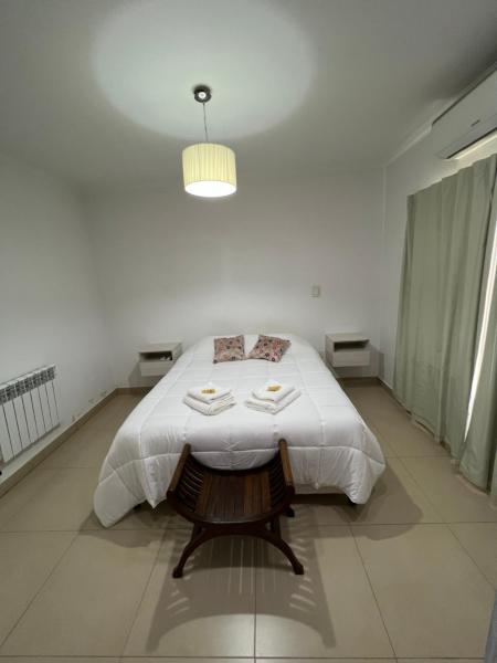 Dormitorio blanco con cama y mesa en Hermosa casa al pie del cerro San Bernardo en Salta