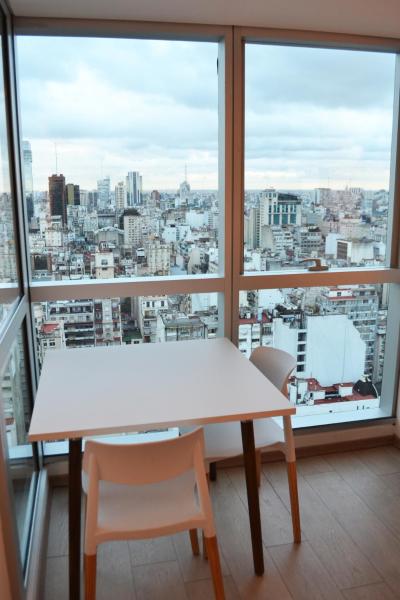 mesa y sillas en una habitación con ventana grande en Blue Dream Esmeralda en Buenos Aires