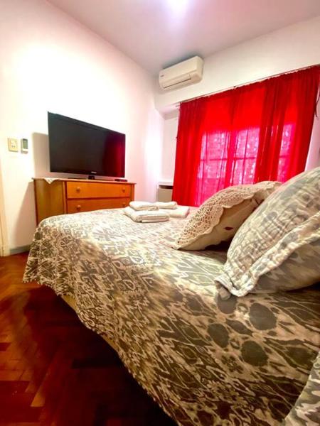 1 dormitorio con 1 cama con cortina roja y TV en Flat in the heart of Mendoza en Mendoza