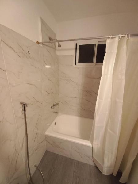 Baño blanco con bañera y cortina de ducha en Edificio Buenos Aires en Buenos Aires