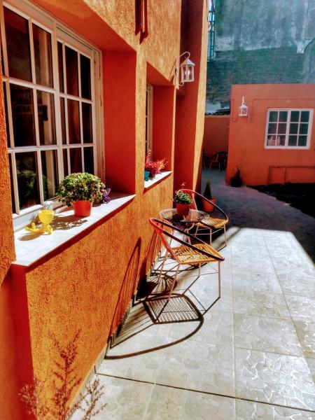 un edificio naranja con 2 sillas en un patio en CASA REINA Apartamentos en Buenos Aires