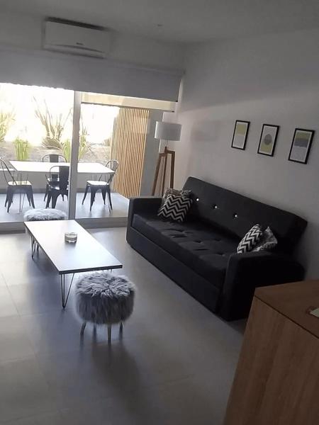 sala de estar con sofá negro y mesa en Pinamar, Complejo Premium en Pinamar Norte en Ostende