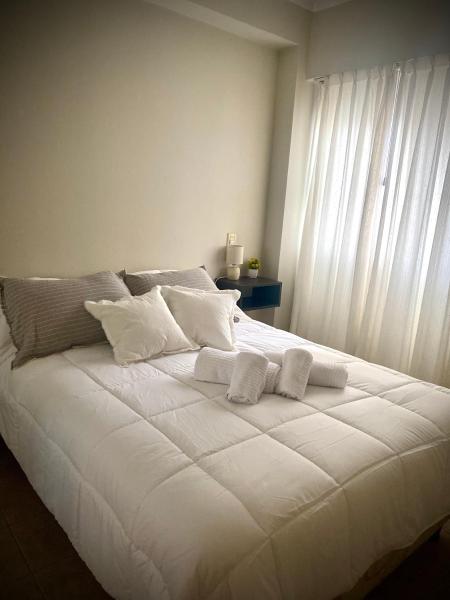 Una gran cama blanca con toallas encima. en Gertrudis - Central Point Apartments en Salta