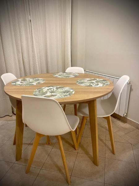 una mesa de madera con sillas blancas alrededor en Gertrudis - Central Point Apartments en Salta