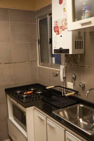 cocina con fregadero y fogones horno superior en Departamento Downtown en Buenos Aires