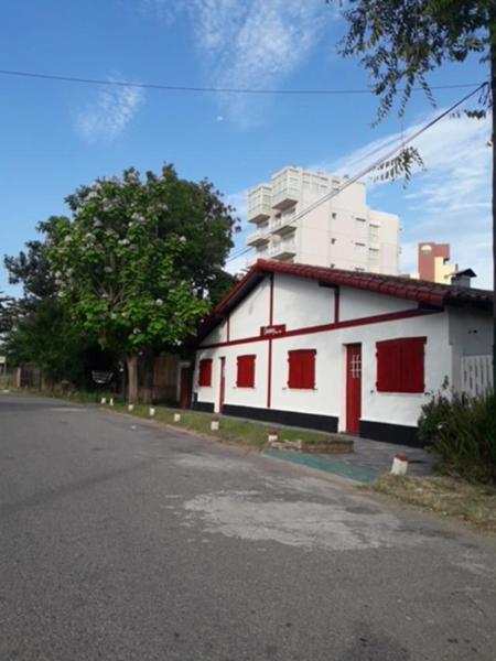 un edificio blanco con puertas rojas junto a una calle en Complex Quimey alojamiento familiar en Villa Gesell