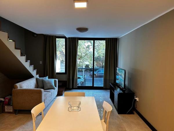 sala de estar con mesa y sofá en Duplex de categoría Unique en Mendoza