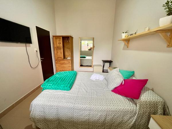 1 dormitorio con 1 cama con almohadas verdes y rosas en Verde Limón casa en San Salvador de Jujuy