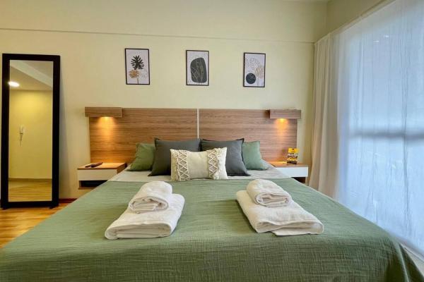 Un dormitorio con una gran cama verde con toallas. en Green Palermo en Buenos Aires