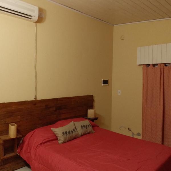 1 dormitorio con 1 cama con colcha roja en Casa hasta 5 personas en Gualeguaychú
