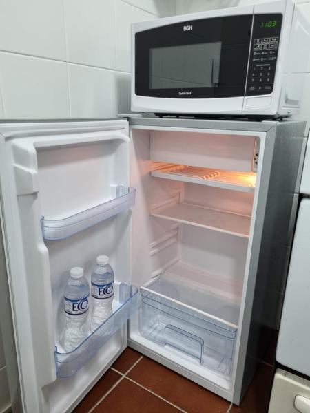 una refrigerador abierta con microondas y botellas de agua. en Departamento en pleno centro Don Bosco 73 en Mendoza
