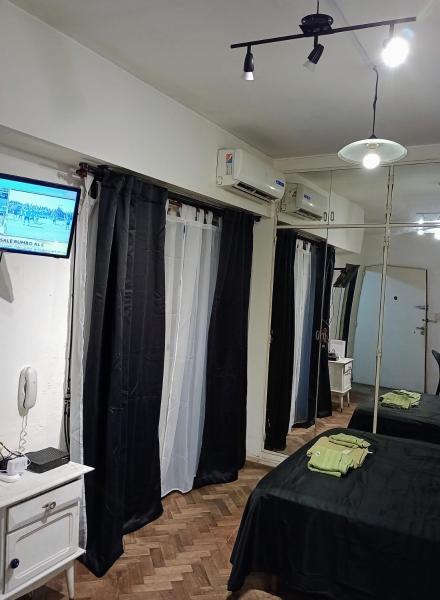 Habitación con cortinas negras, cama y TV. en Departamento en Recoleta en Buenos Aires